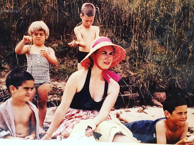 Corrine Koslo's mother in a pink hat and black sleeveless sitting with her kids.